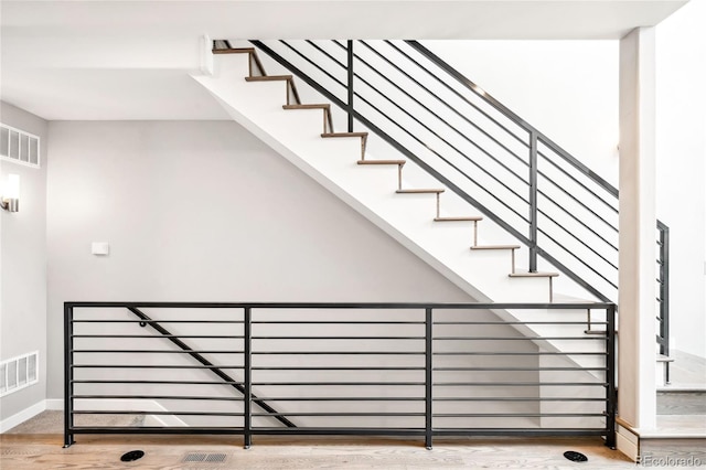 staircase featuring baseboards, visible vents, and wood finished floors