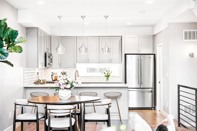 kitchen with stainless steel appliances, a peninsula, light countertops, and visible vents