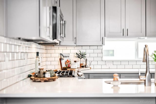 kitchen with stainless steel microwave, gray cabinets, and decorative backsplash