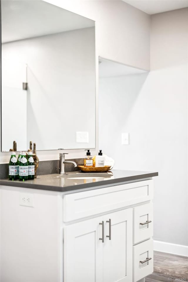 bathroom with baseboards, wood finished floors, and vanity