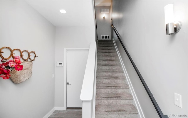 stairway with recessed lighting, wood finished floors, visible vents, and baseboards