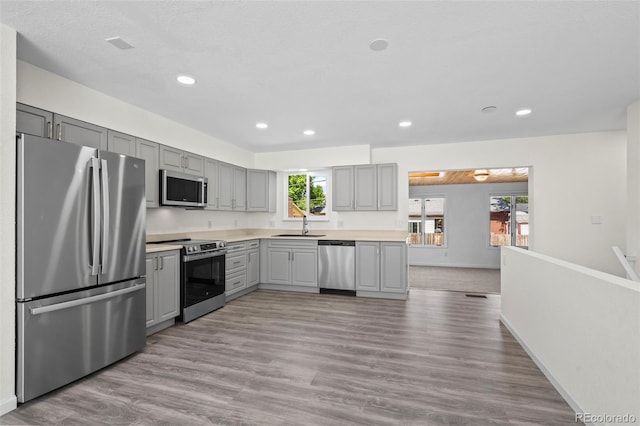 1035 Iris St, Broomfield, CO 80020 - kitchen with appliances with stainless steel finishes, gray cabinetry, recessed lighting, light wood finished floors, and light countertops