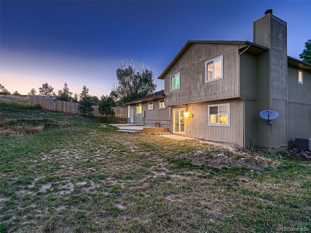 8916 Sunridge Hollow Rd, Parker, CO 80134 - back of property at dusk with a chimney, central AC, fence, a yard, and a patio