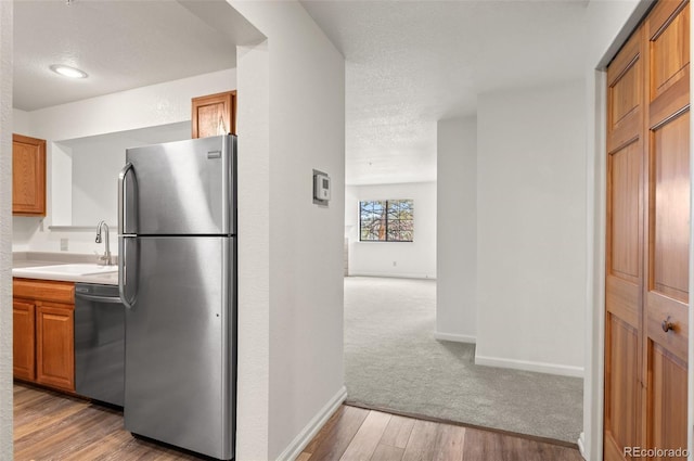 kitchen featuring a sink, stainless steel appliances, brown cabinetry, and light countertops