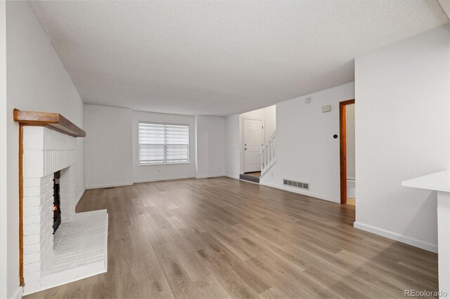1770 S Quintero Way, Aurora, CO 80017 - unfurnished living room with light wood finished floors, stairs, a textured ceiling, and visible vents