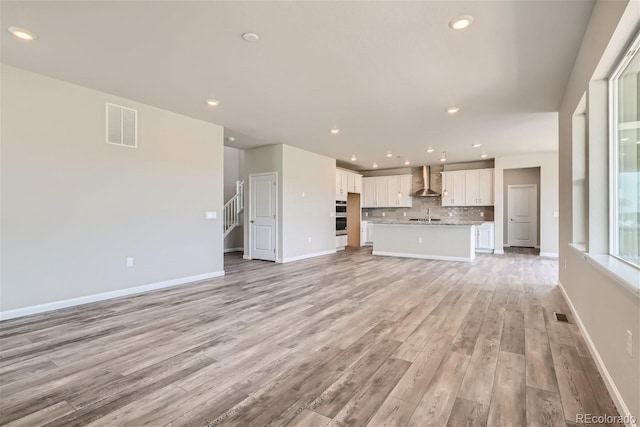 unfurnished living room with light hardwood / wood-style flooring and sink