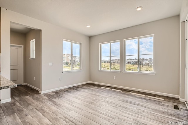 unfurnished room with a healthy amount of sunlight and light hardwood / wood-style floors