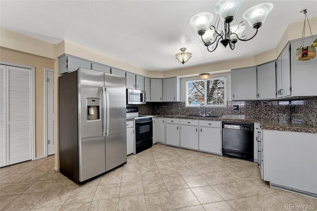 kitchen featuring a sink, appliances with stainless steel finishes, backsplash, gray cabinets, and dark countertops