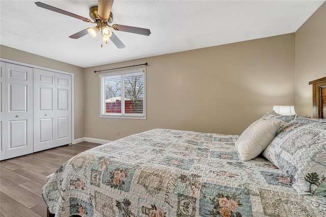 bedroom featuring a closet, ceiling fan, a textured ceiling, wood finished floors, and baseboards