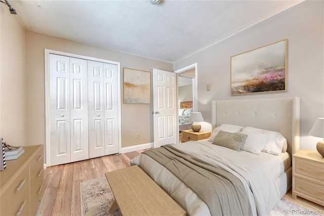 bedroom featuring light wood-type flooring, baseboards, and a closet