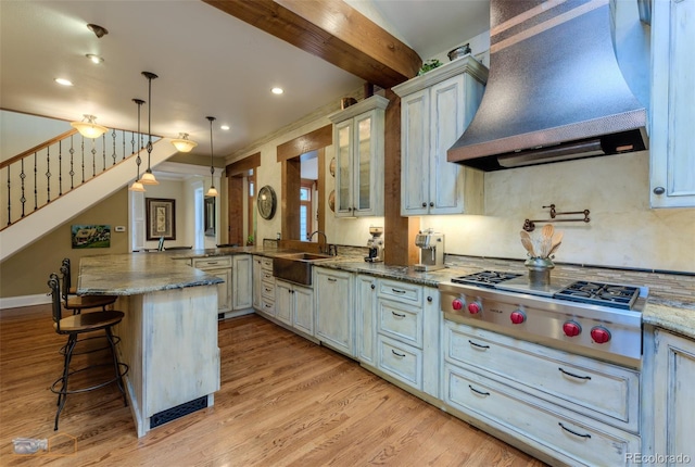 3737 26th St, Boulder, CO 80304 - kitchen with custom range hood, a peninsula, a breakfast bar, stainless steel gas cooktop, and light wood-style floors