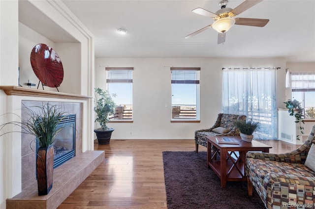 living room with wood-type flooring, a fireplace, and ceiling fan