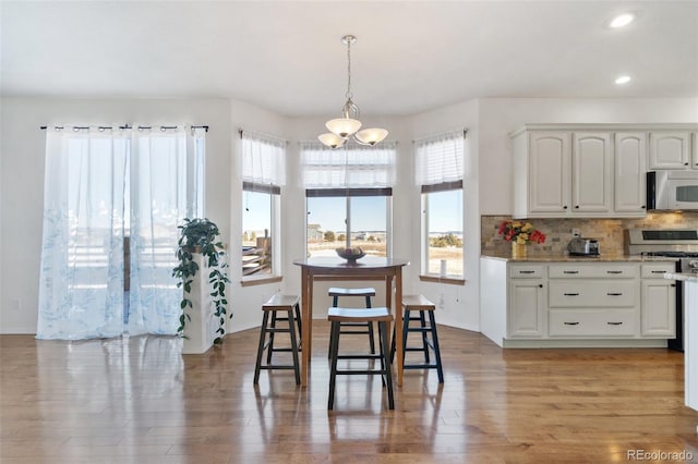 dining room featuring an inviting chandelier, light wood-type flooring, and plenty of natural light