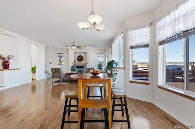 dining space featuring ceiling fan with notable chandelier and light hardwood / wood-style floors