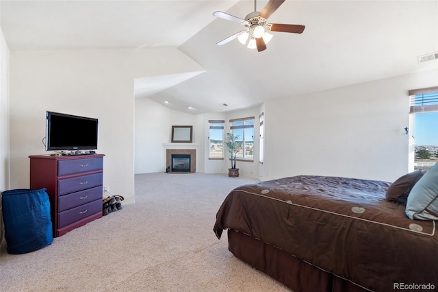 carpeted bedroom featuring a tile fireplace, ceiling fan, and vaulted ceiling