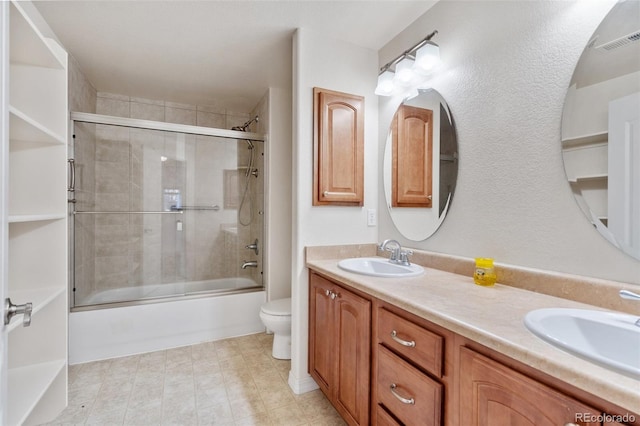 full bathroom with enclosed tub / shower combo, vanity, and toilet