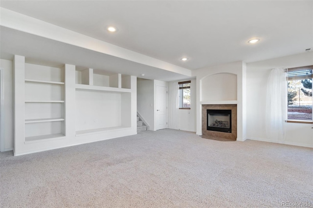 unfurnished living room featuring built in shelves, light colored carpet, and a fireplace