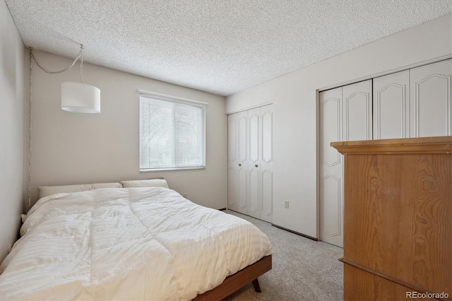 carpeted bedroom featuring multiple closets and a textured ceiling