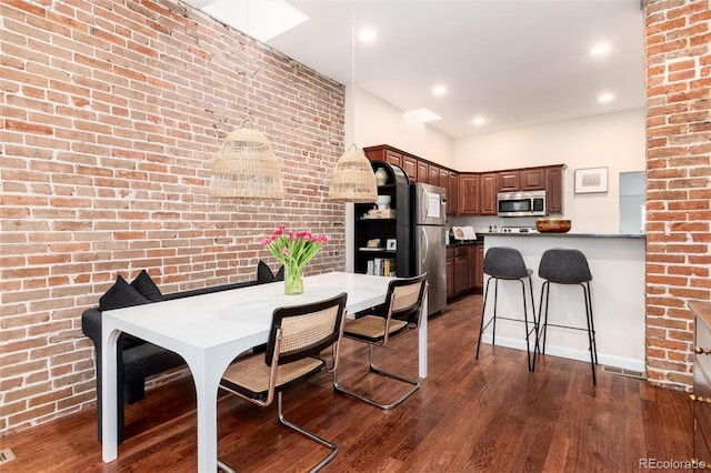dining space with brick wall, dark wood-style flooring, baseboards, and visible vents