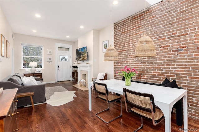 dining area with recessed lighting, baseboards, brick wall, a fireplace with flush hearth, and wood finished floors