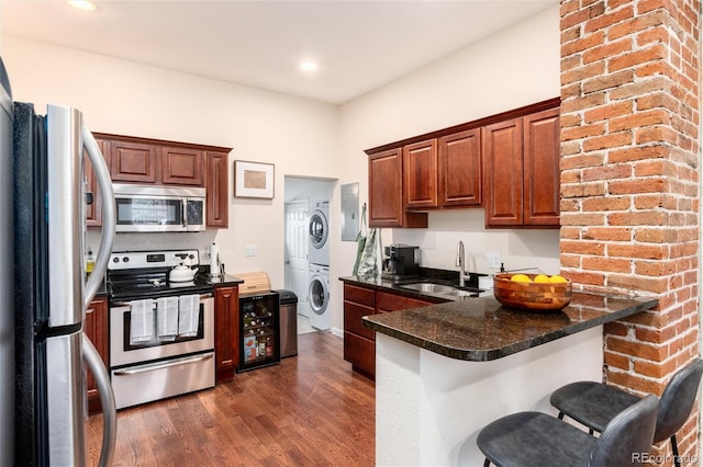 3220 W 24th Ave, Denver, CO 80211 - kitchen featuring a sink, a peninsula, stainless steel appliances, stacked washer / dryer, and dark wood-type flooring