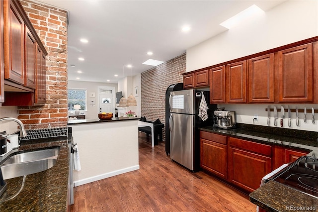 kitchen with a peninsula, wood finished floors, a sink, freestanding refrigerator, and black electric range oven