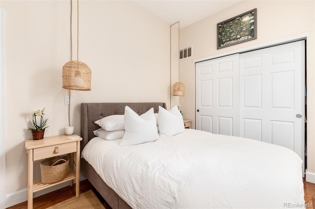 bedroom featuring a closet, baseboards, visible vents, and wood finished floors