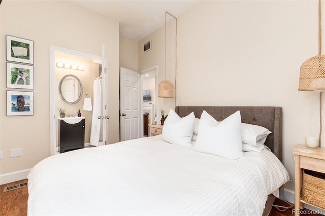 bedroom featuring baseboards, visible vents, and wood finished floors