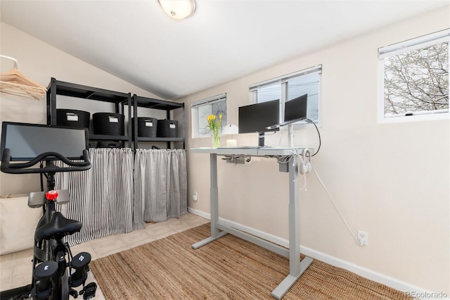 exercise room with lofted ceiling, baseboards, and tile patterned floors