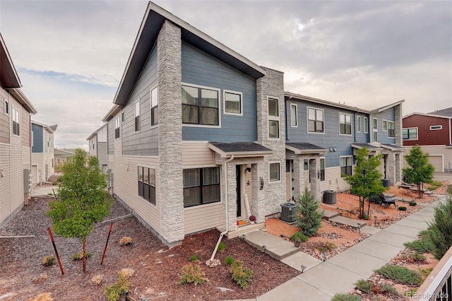 view of front of property featuring central AC unit, stone siding, and a residential view