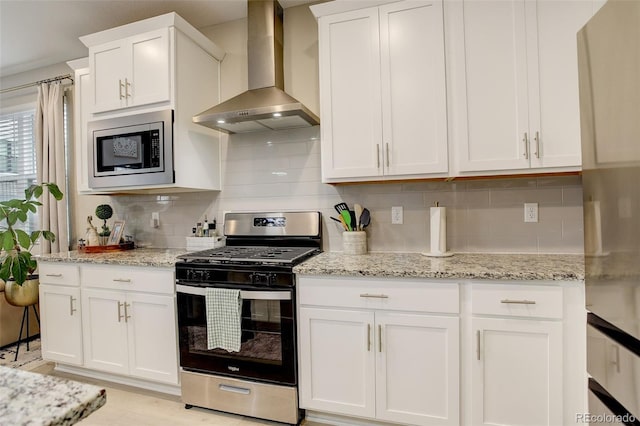 9279 Merino Ct Unit D, Littleton, CO 80125 - kitchen featuring appliances with stainless steel finishes, wall chimney range hood, backsplash, white cabinets, and light stone countertops