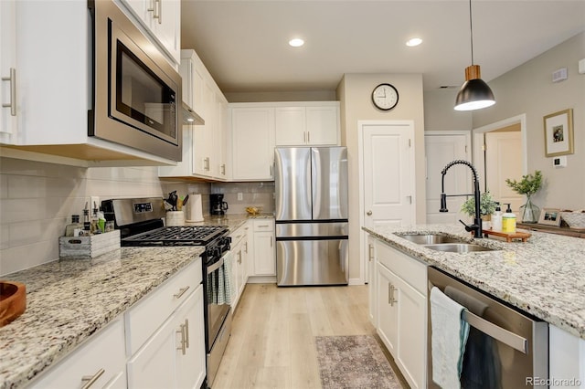 9279 Merino Ct Unit D, Littleton, CO 80125 - kitchen with stainless steel appliances, a sink, white cabinets, light wood-style flooring, and backsplash