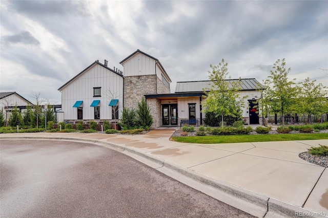 9279 Merino Ct Unit D, Littleton, CO 80125 - view of front facade featuring stone siding, french doors, board and batten siding, a standing seam roof, and metal roof