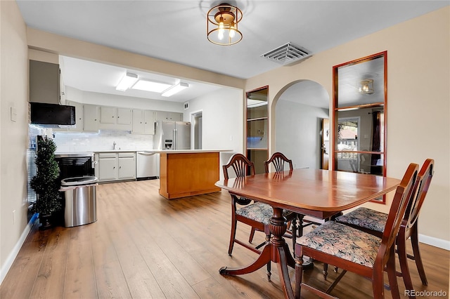 891 Ursula St, Aurora, CO 80011 - dining area featuring arched walkways, light wood-type flooring, and baseboards