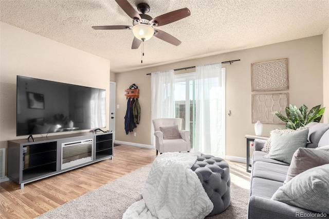 living room featuring visible vents, a textured ceiling, wood finished floors, baseboards, and ceiling fan