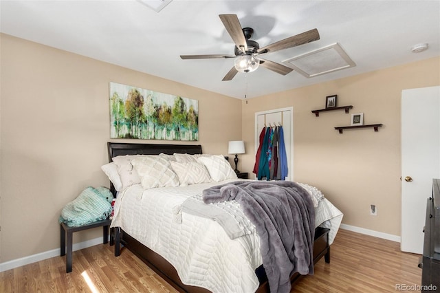 bedroom featuring baseboards, attic access, ceiling fan, light wood-style floors, and a closet