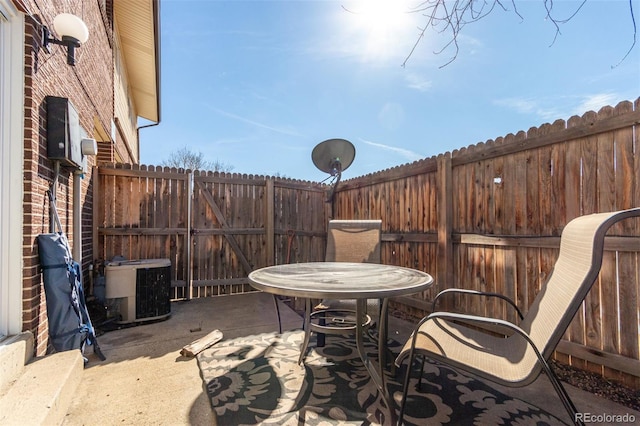 view of patio with cooling unit, outdoor dining area, and a fenced backyard