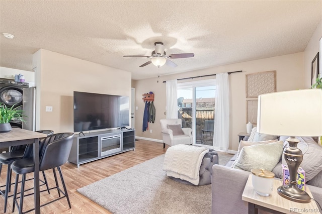 living room with ceiling fan, baseboards, a textured ceiling, and wood finished floors