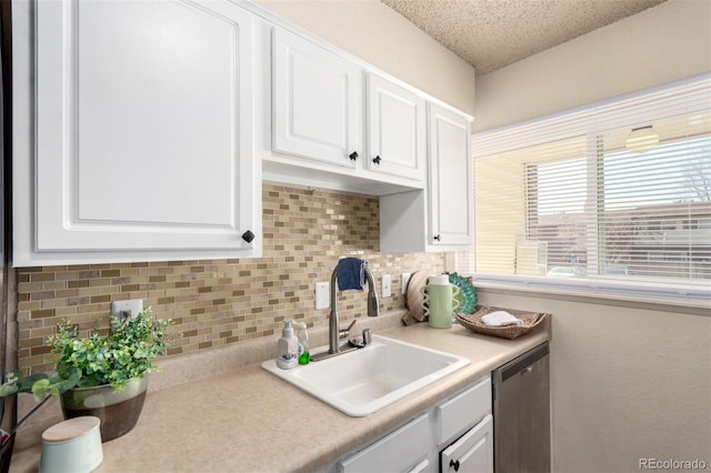 kitchen with a sink, decorative backsplash, light countertops, white cabinets, and dishwasher