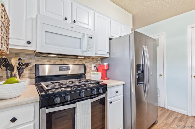 kitchen with light countertops, white cabinets, light wood-style flooring, and appliances with stainless steel finishes