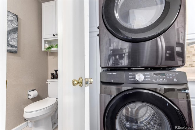 clothes washing area with laundry area, stacked washer and dryer, and a textured wall