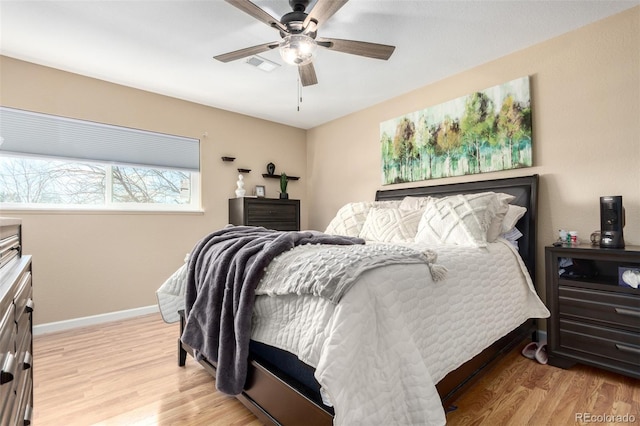 bedroom featuring light wood finished floors, visible vents, a ceiling fan, and baseboards