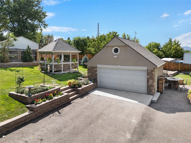 view of front of home featuring a gazebo, a front lawn, an outdoor structure, and a garage