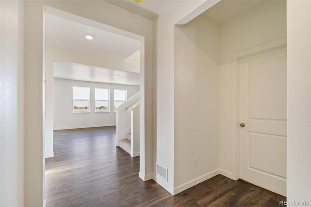 hall featuring visible vents, baseboards, dark wood finished floors, and stairs