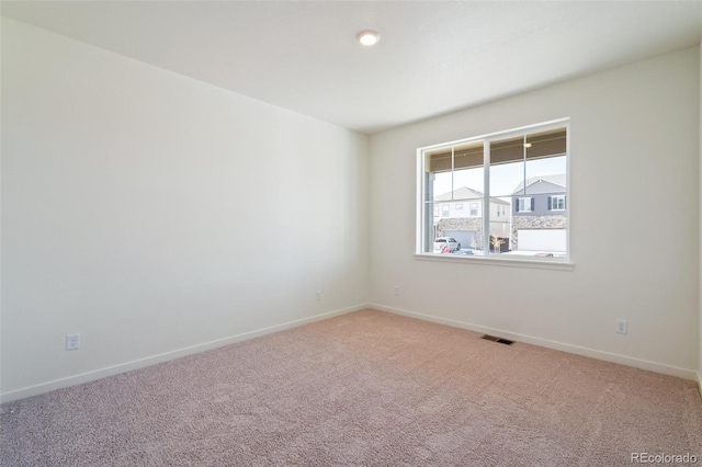 spare room with visible vents, light colored carpet, and baseboards