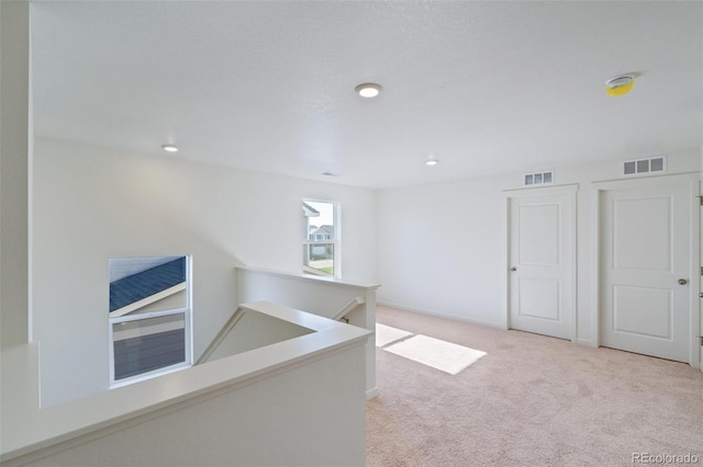 interior space featuring carpet, an upstairs landing, visible vents, and baseboards