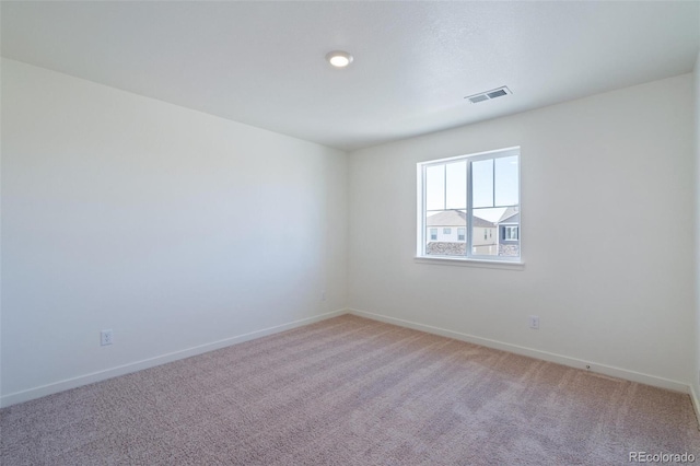 spare room featuring baseboards, visible vents, and light carpet