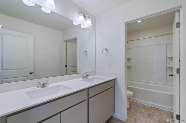 bathroom with double vanity, toilet,  shower combination, and a sink