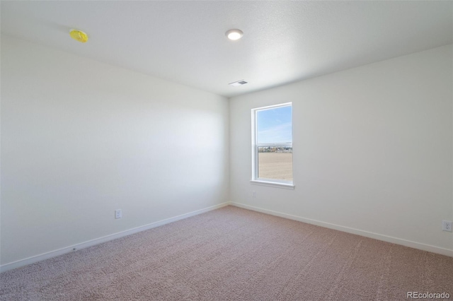 spare room featuring visible vents, baseboards, and light carpet