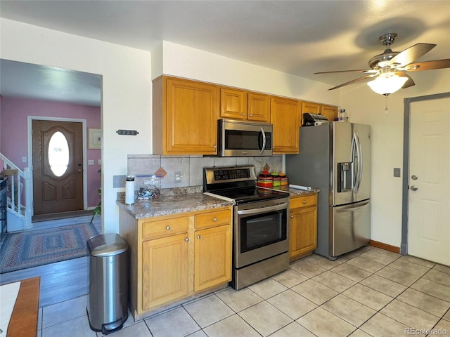 4383 S Eagle Cir, Aurora, CO 80015 - kitchen with appliances with stainless steel finishes, decorative backsplash, a ceiling fan, light tile patterned floors, and brown cabinetry